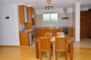 Modern fully equipped kitchen at The Moon Serenity Fourways Branch at Lymack Suites in Nairobi featuring fitted cabinets, dining area, kitchen appliances and contemporary interior finishes